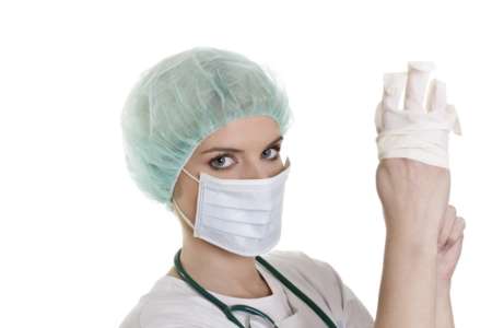 Женщина-врач надевает перчатки